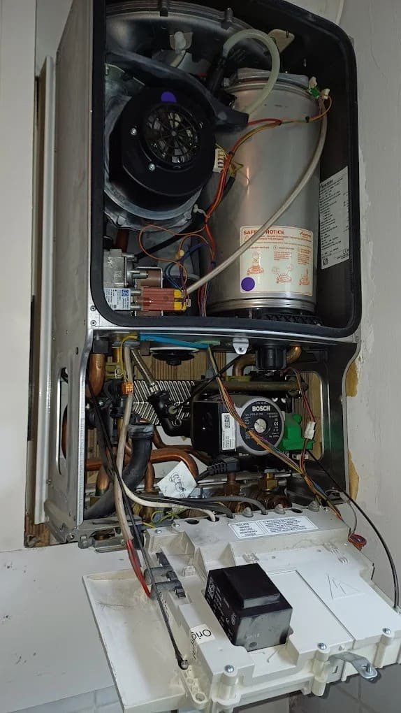 Engineer servicing the internal components of a wall-hung boiler