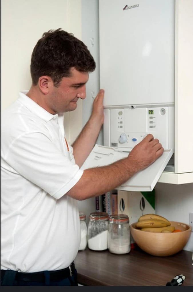 Engineer adjusting boiler controls and commissioning the system
