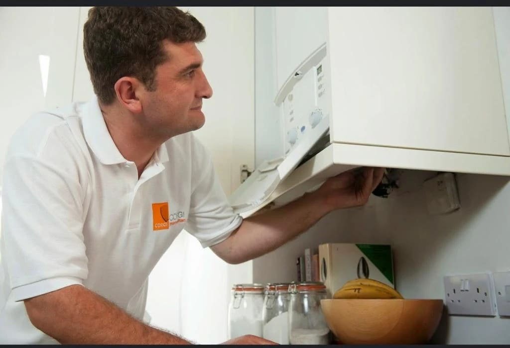 AM Heating engineer working on a boiler inside a kitchen cabinet