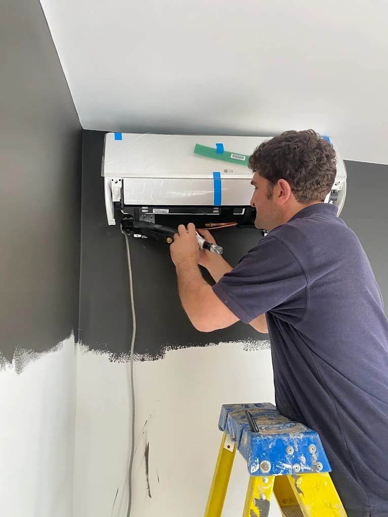 Engineer installing a wall-mounted indoor air conditioning unit in a London home