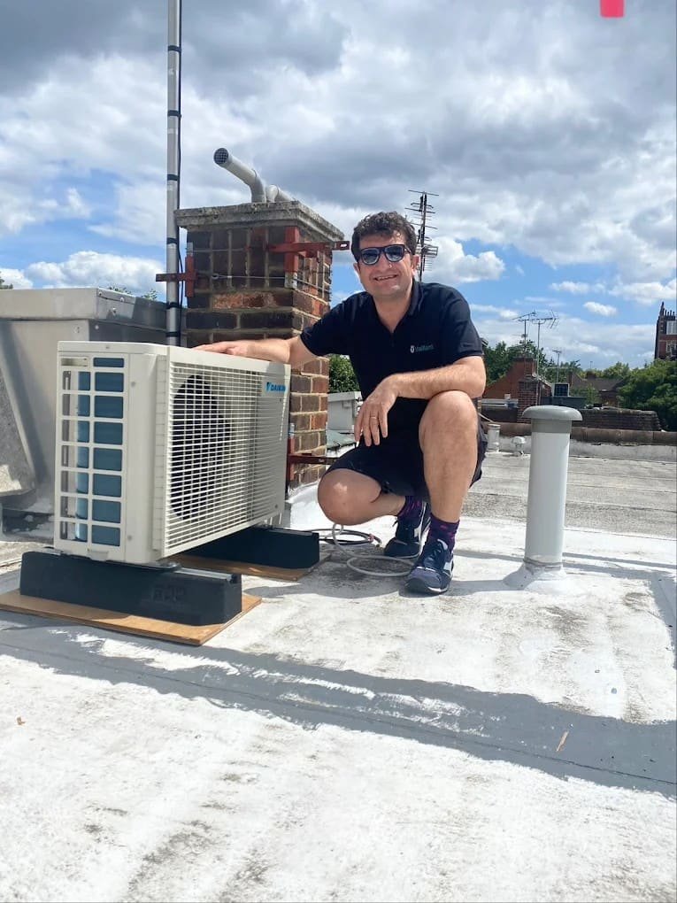 AM Heating engineer commissioning an outdoor AC unit on a London rooftop
